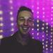 Photo of Daniel Brew, smiling man against shining magenta background