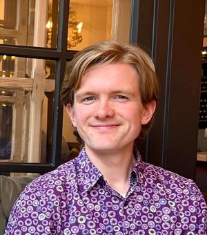 Headshot of student Barnett, wearing purple shirt and smiling at the camera